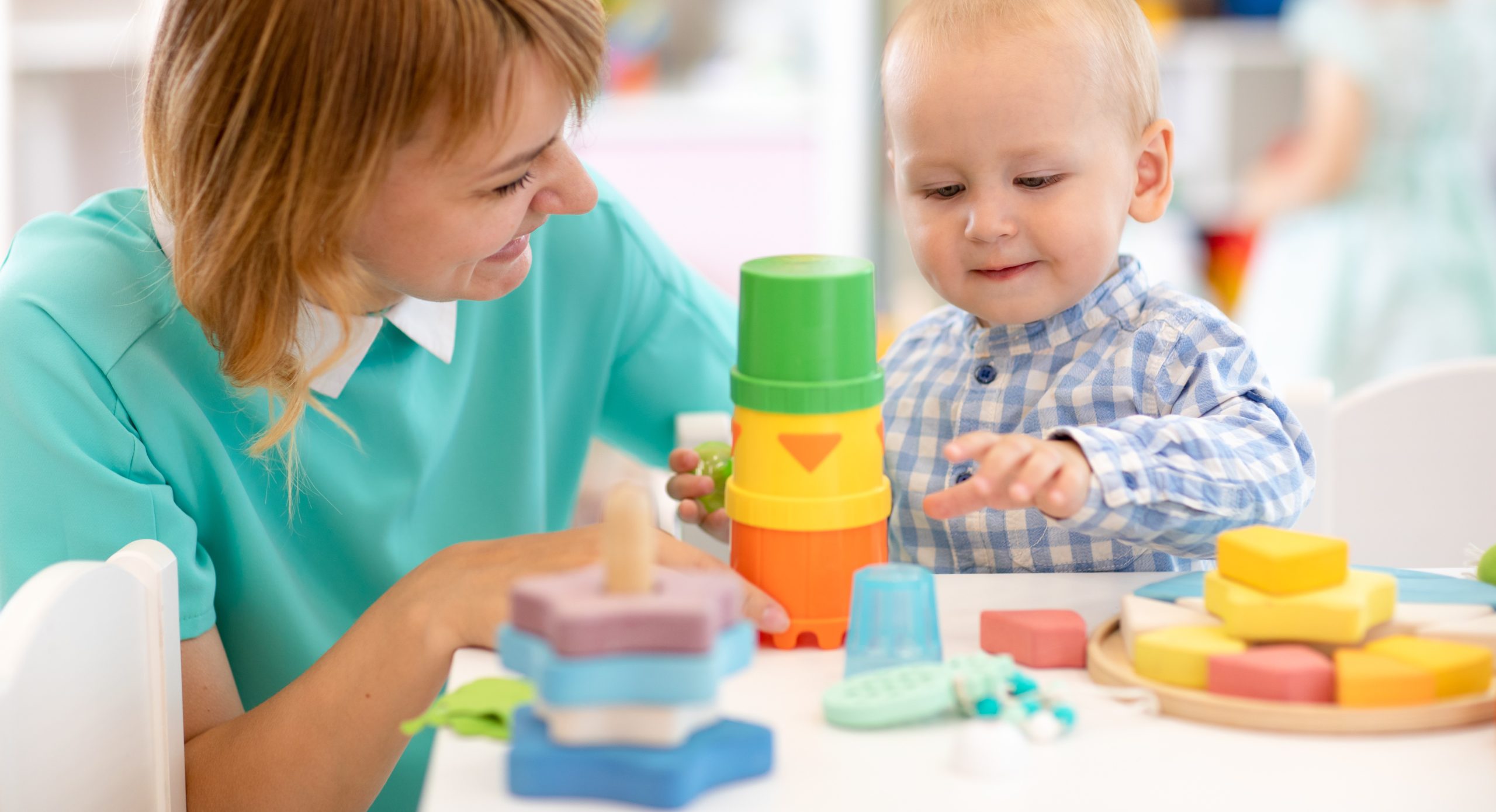 Assistante maternelle qui joue à la pate à modeler avec un bébé