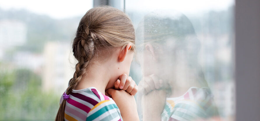 Petite fille regardant de manière triste par la fenêtre